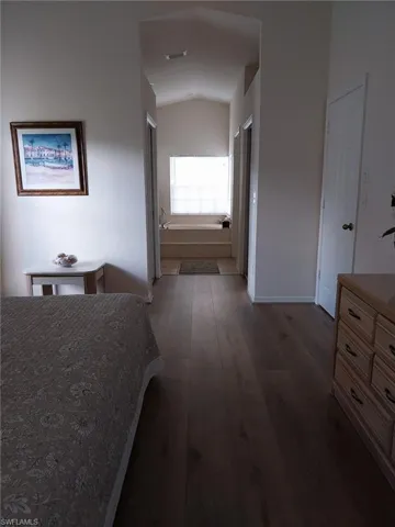 Bedroom featuring dark wood-style floors and lofted ceiling