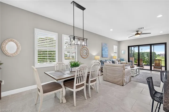 Open-concept space featuring tile flooring, plantation shutters, a linear multi-light pendant fixture, recessed lighting, and expansive multi-panel glass sliding doors