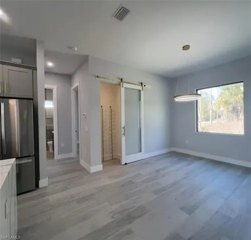 Unfurnished dining area featuring a barn door and light wood-type flooring