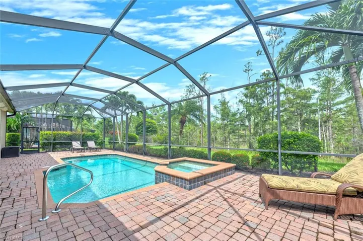 View of pool featuring a sunroom, a lanai, a pool with connected hot tub, and a patio