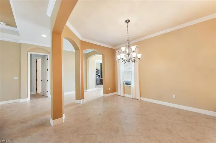 Spare room with arched walkways, a chandelier, crown molding, light tile patterned flooring, and recessed lighting