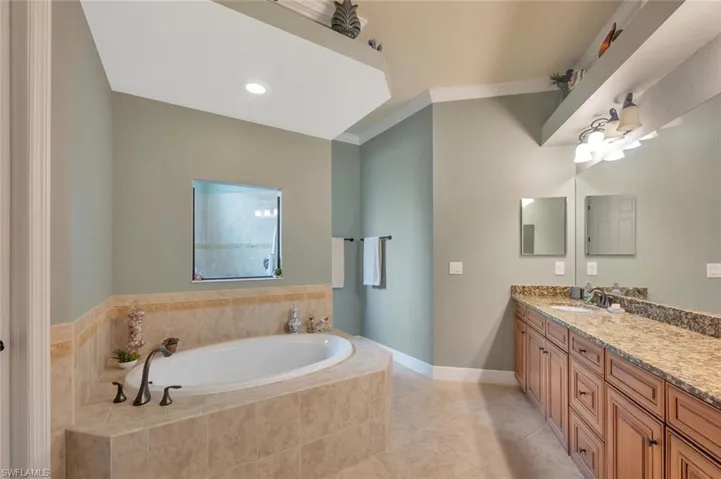 Bathroom featuring ornamental molding, a bath, vanity, light tile patterned flooring, and recessed lighting