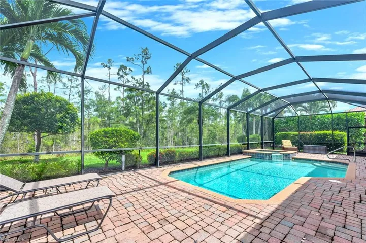 View of swimming pool featuring a sunroom, a lanai, a pool with connected hot tub, and a patio