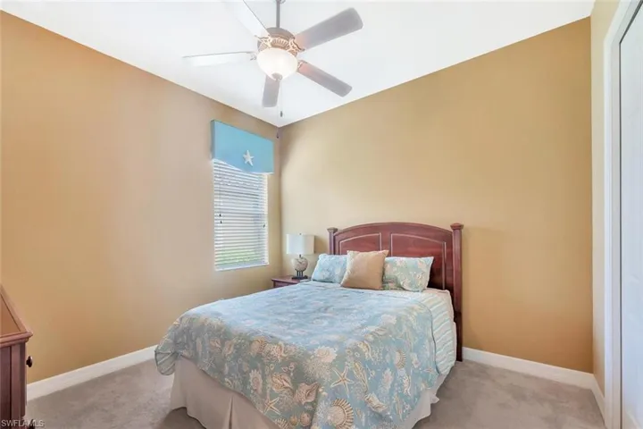 Carpeted bedroom with ceiling fan and baseboards