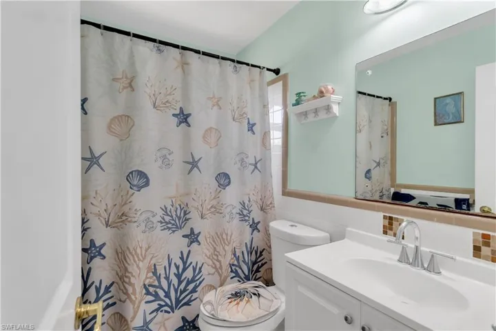 Bathroom featuring vanity, a bathtub with shower curtain, tile walls, and toilet