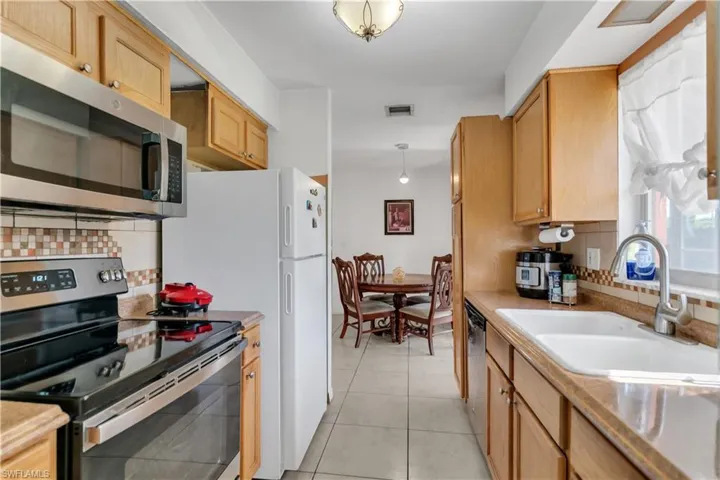 Kitchen featuring light  patterned floors, backsplash, stainless steel appliances, and sink