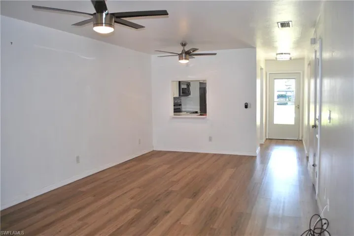 Unfurnished living room with wood finished floors and a ceiling fan