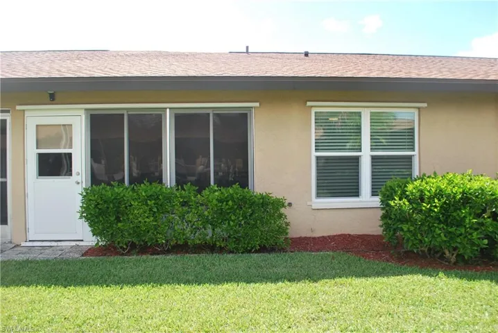 View of side of property featuring stucco siding, a yard, and roof with shingles