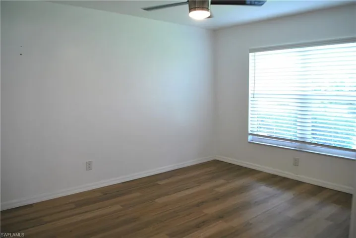 Primary bed room with dark wood-style flooring and ceiling fan