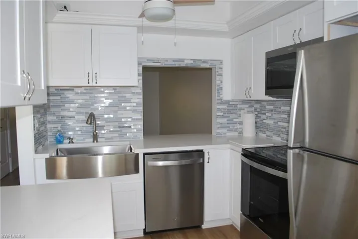 Kitchen with stainless steel appliances, white cabinetry, tasteful backsplash, and light stone counters