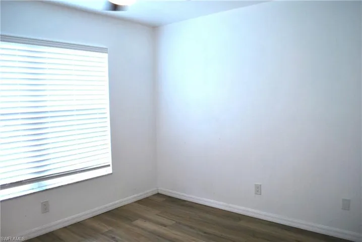 Spare room featuring dark wood-type flooring and baseboards