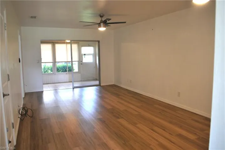 Empty room featuring dark wood-type flooring and a ceiling fan