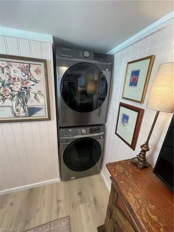 Laundry area with light wood-type flooring and stacked washer / drying machine