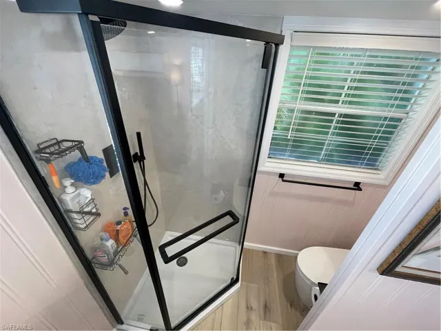 Bathroom featuring a shower stall and light wood-type flooring