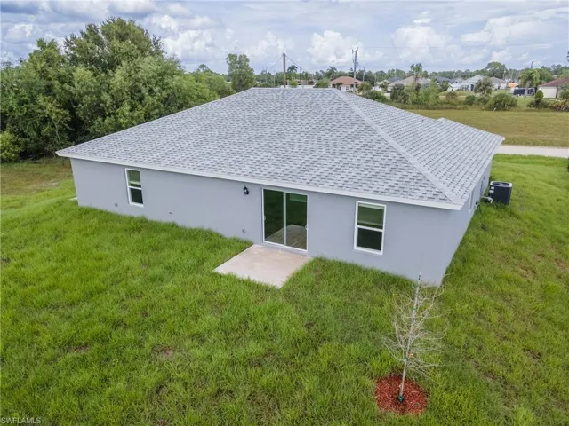 Rear view of house with a lawn, a patio area, and central AC