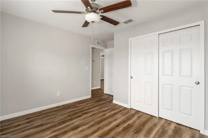Unfurnished bedroom with dark hardwood / wood-style floors, ceiling fan, and a closet