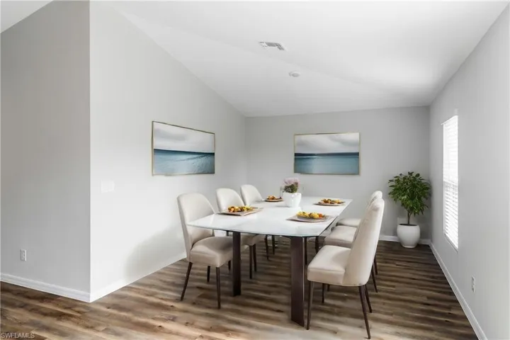Dining room with vaulted ceiling, a wealth of natural light, and dark wood-type flooring