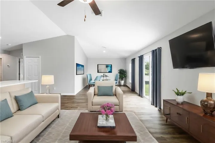 Living room with hardwood / wood-style floors, ceiling fan, and lofted ceiling