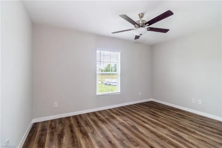 Empty room with ceiling fan and dark wood-type flooring