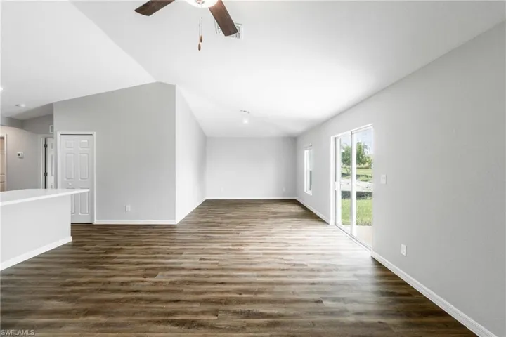 Unfurnished living room featuring vaulted ceiling, ceiling fan, and dark wood-type flooring