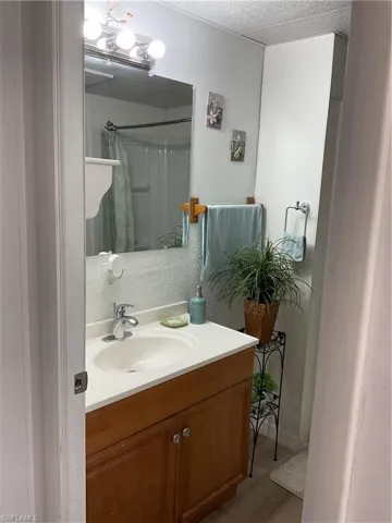 Bathroom with vanity, a textured ceiling, and walk in shower