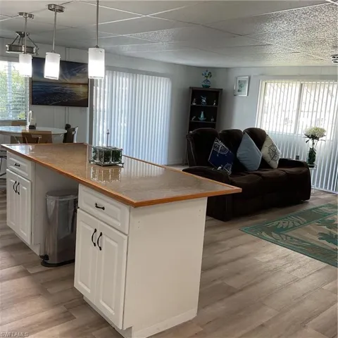 Kitchen featuring white cabinetry, hanging light fixtures, light hardwood / wood-style flooring, a kitchen island, and a wealth of natural light