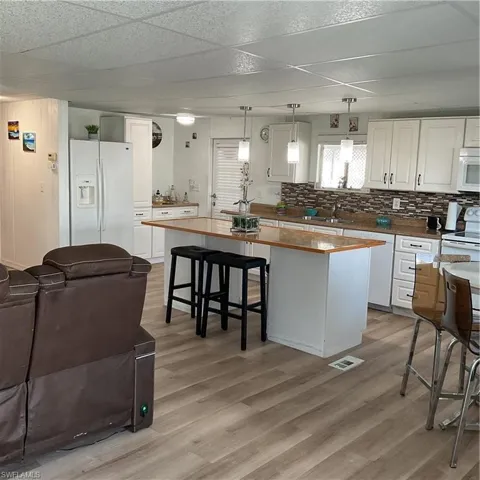 Kitchen featuring white cabinetry, hanging light fixtures, a center island, and refrigerator