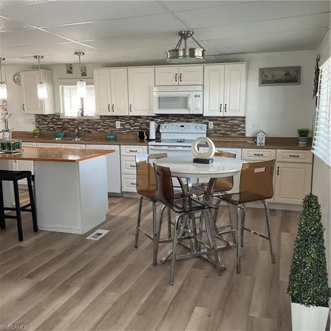 Kitchen featuring stove, light hardwood / wood-style flooring, white cabinets, and decorative light fixtures