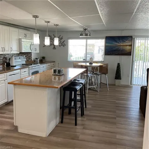 Kitchen with dishwashing machine, stove, hardwood / wood-style floors, a center island, and white cabinets