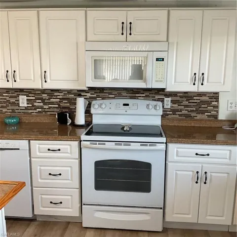Kitchen with white cabinetry, dishwasher, decorative backsplash, and electric range