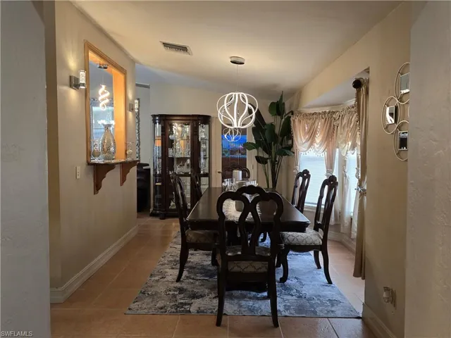 Tiled dining area with lofted ceiling and a chandelier