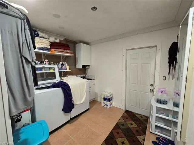 Laundry room with cabinets and light tile floors