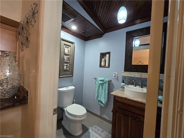 Bathroom featuring wooden ceiling, ornamental molding, toilet, and oversized vanity