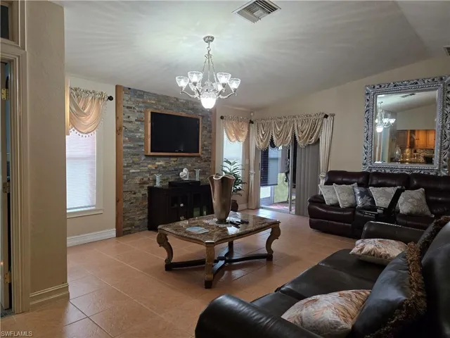 Living room featuring a notable chandelier, tile flooring, plenty of natural light, and lofted ceiling