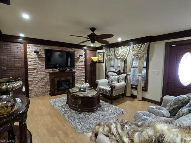 Living room featuring ceiling fan, crown molding, and light wood-type flooring