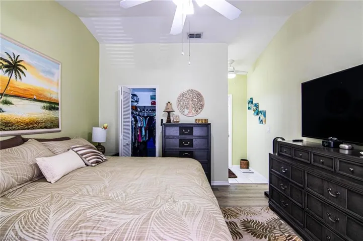 Bedroom with ceiling fan, a spacious closet, light hardwood / wood-style floors, lofted ceiling, and a closet