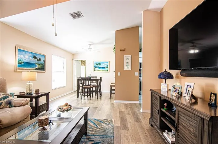 Living room with light hardwood / wood-style floors, ceiling fan, and lofted ceiling