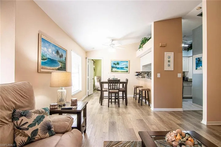 Living room with ceiling fan, light hardwood / wood-style floors, and vaulted ceiling