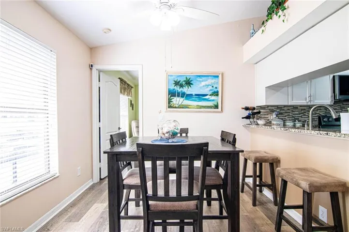 Dining space with ceiling fan, sink, vaulted ceiling, and light hardwood / wood-style flooring