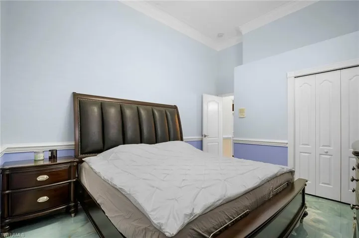 Tiled bedroom with crown molding and a closet