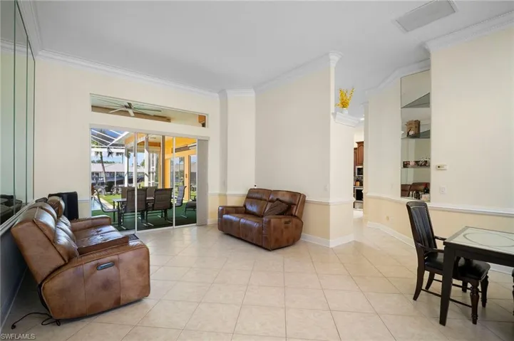 Living room featuring crown molding, a sunroom, tile patterned flooring, and ceiling fan