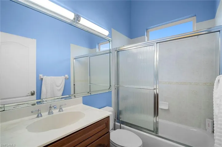 Bathroom featuring vanity, plenty of natural light, and shower / bath combination with glass door