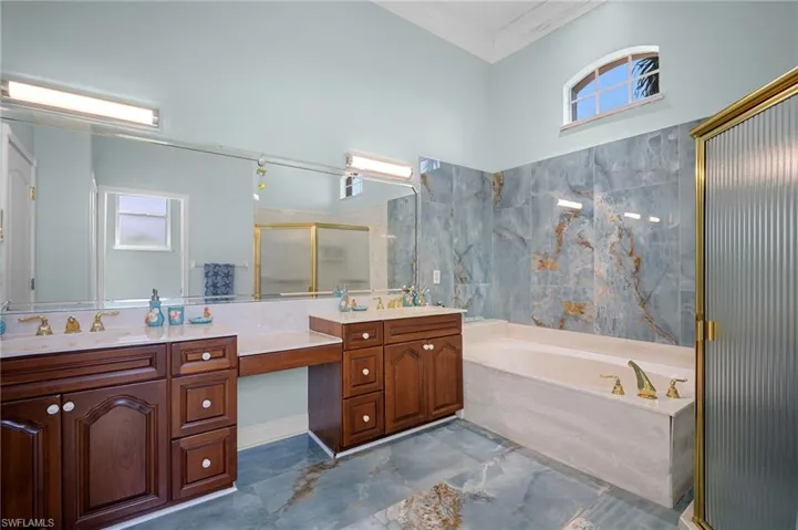 Full bathroom featuring a stall shower, a bath, double vanity, and crown molding
