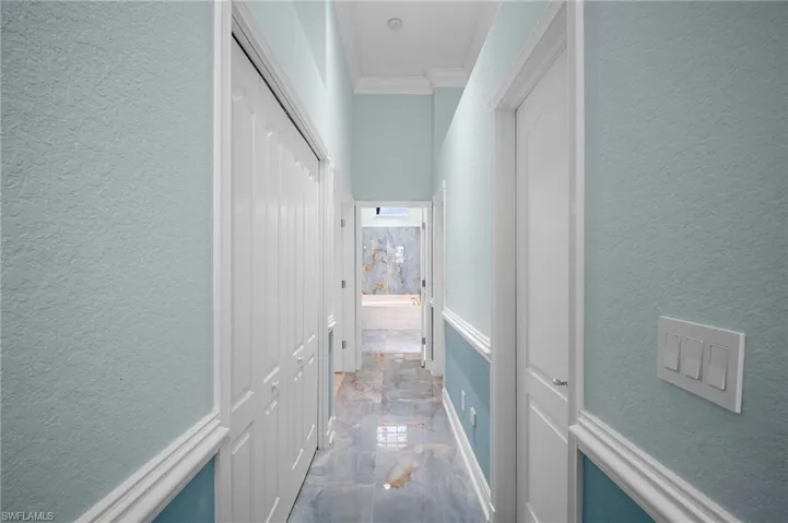 Hall with a textured wall and crown molding