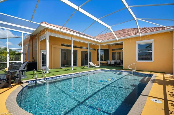 Back of property featuring a sunroom, ceiling fan, glass enclosure, an outdoor pool, and a patio area