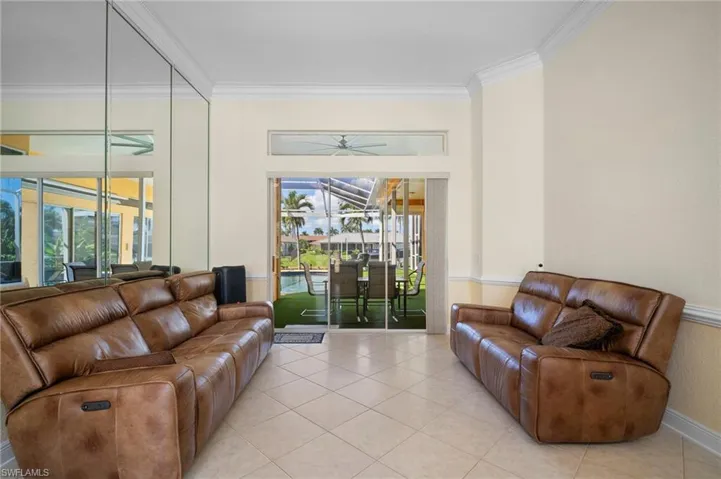 Living area featuring a sunroom, tile patterned flooring, and crown molding
