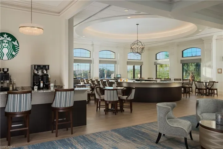 Bar featuring wood finished floors, healthy amount of natural light, ornamental molding, a high ceiling, and decorative light fixtures