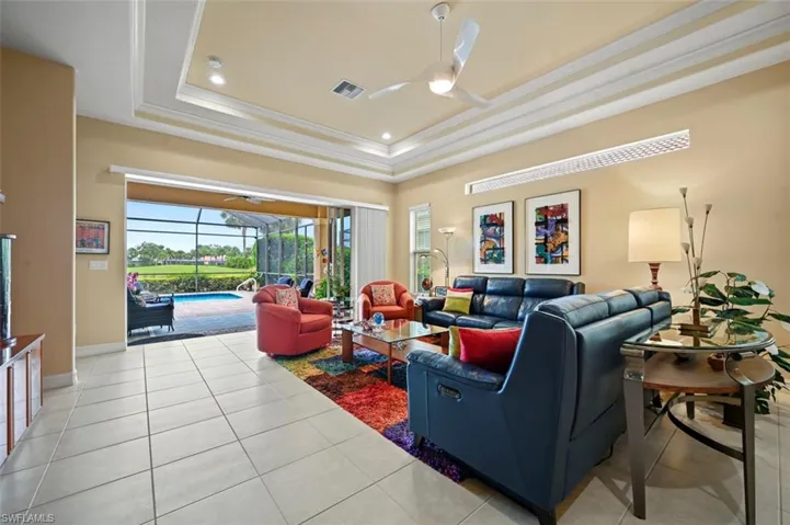Living area featuring ceiling fan, a tray ceiling, a sunroom, light tile patterned floors, and ornamental molding