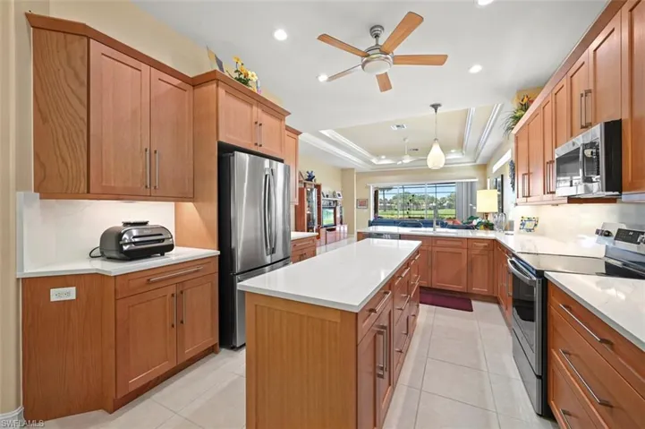 Kitchen featuring appliances with stainless steel finishes, a raised ceiling, a ceiling fan, light countertops, and recessed lighting