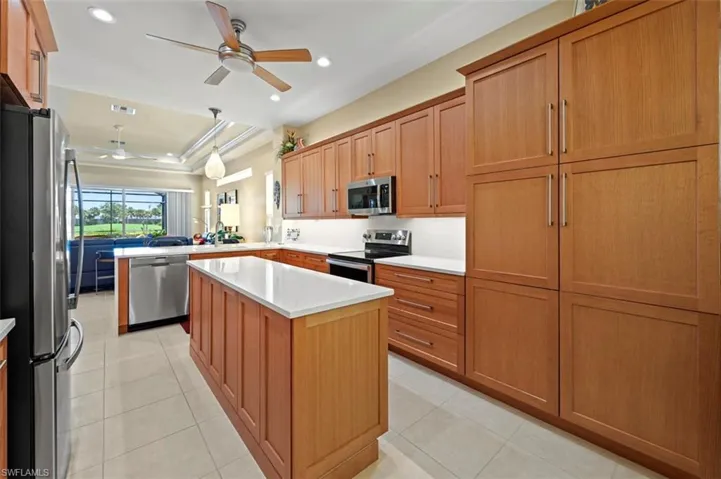 Kitchen with stainless steel appliances, ceiling fan, a peninsula, light countertops, and light tile patterned floors
